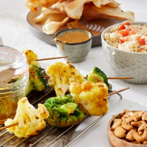Bloemkool en broccolispiesen met kurkuma-olie, bulgursalade, cashewnotensaus & pappadums